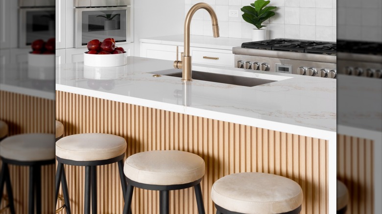 A modern kitchen with fluted wood paneling around the kitchen island