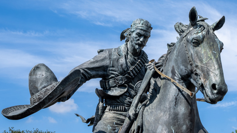 A statue of a Mexican vaquero on horseback, holding his hat in one hand