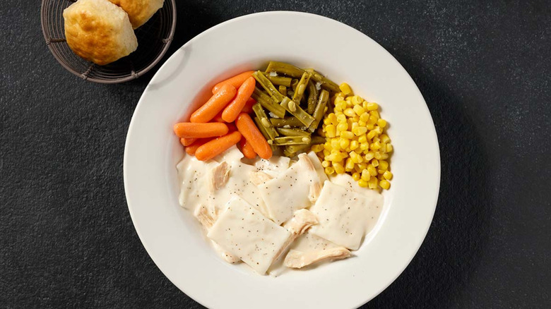 White plated chicken, dumplings, carrots, green beans, corn, biscuits