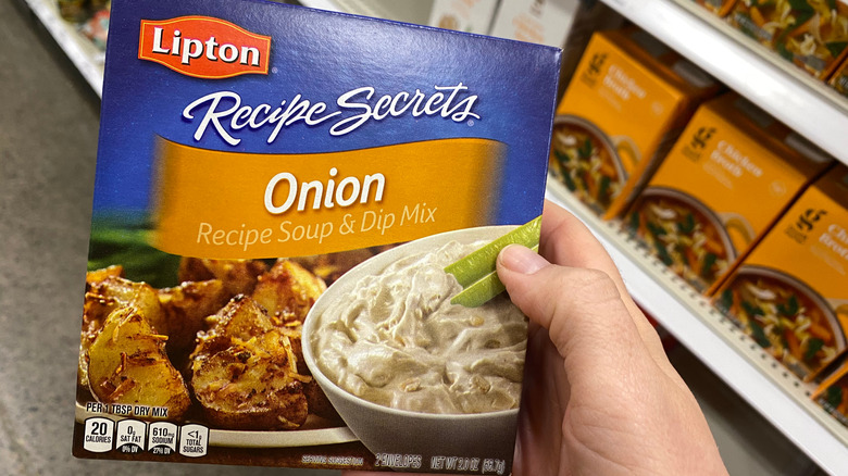 Someone holding a box of Lipton recipe secrets onion soup and dip mix in a grocery store