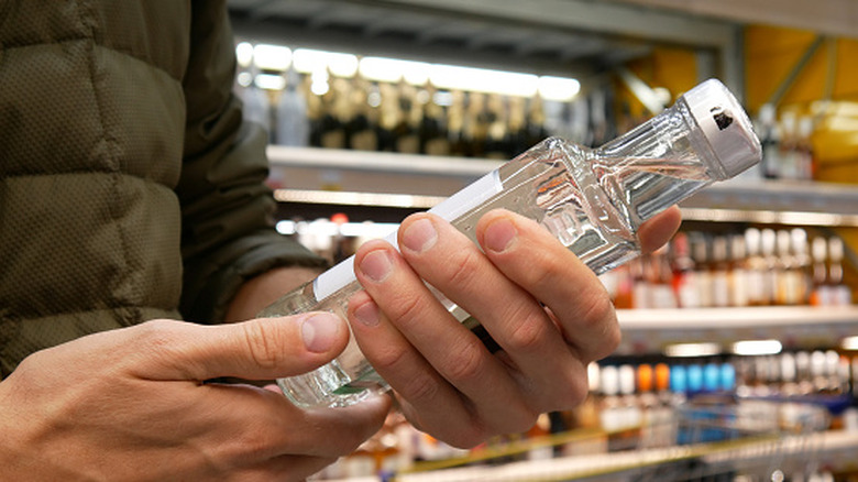 Vodka bottle held by shopper in store