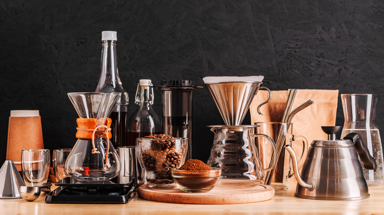 Coffee brewers and other coffee equipment on a wood table in front of a black backdrop