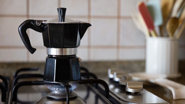 A black moka pot on a gas range in a home kitchen