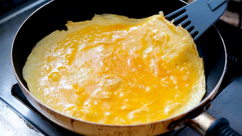 cooking omelet in pan with spatula