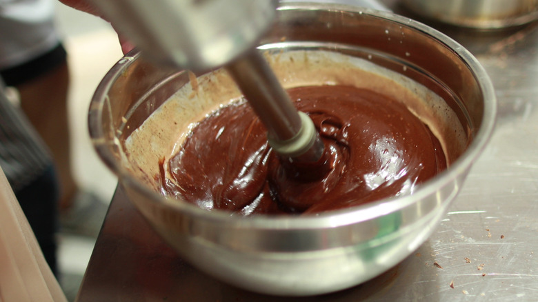 Overhead view of person preparing melted chocolate with an immersion blender