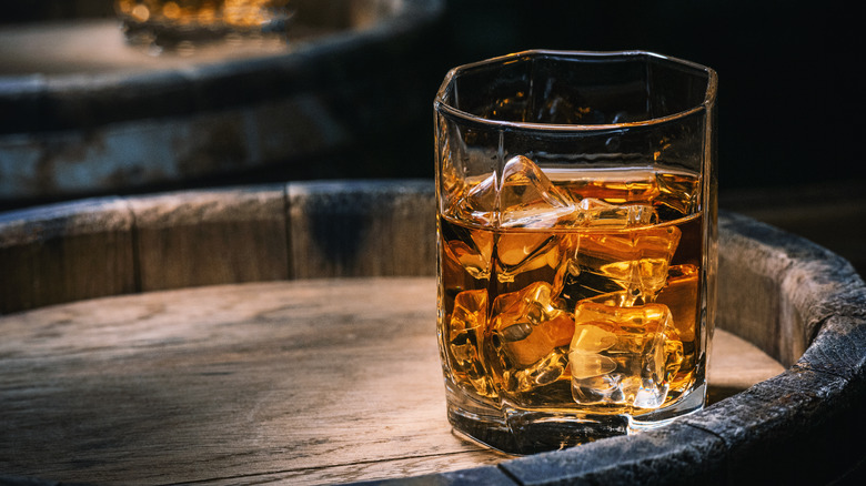 glass of bourbon displayed on barrel