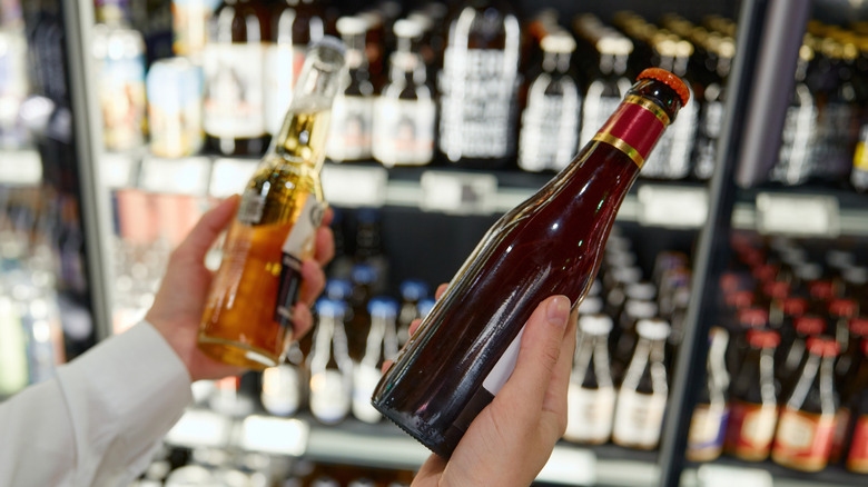 Person holding two unidentified beers in a liquor store