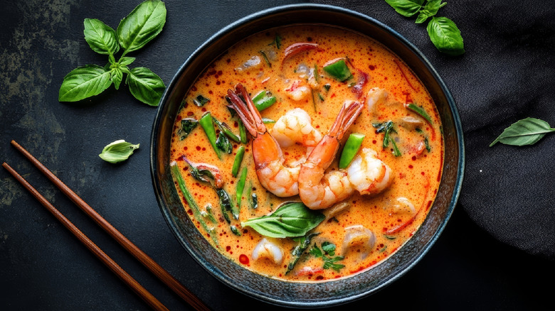 Tom yum soup in a black bowl with shrimp