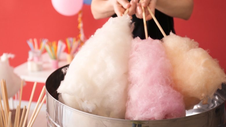 person holding three sticks of cotton candy