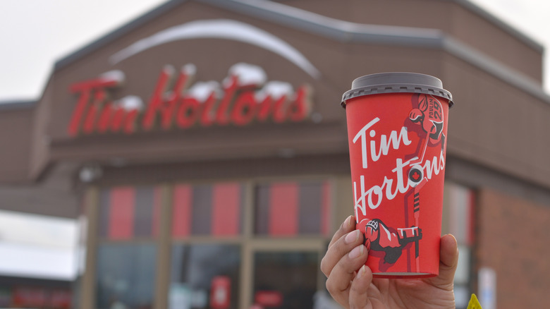 holding up tim hortons coffee cup