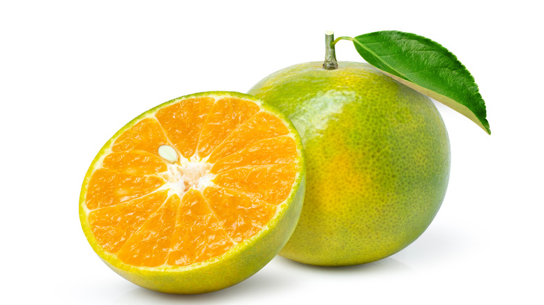 Whole orange and half orange with green skin or peel