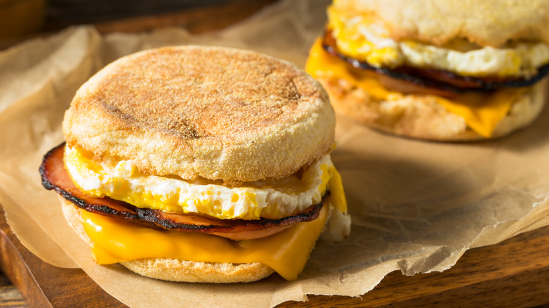 Two English muffin breakfast sandwiches sit on baking paper