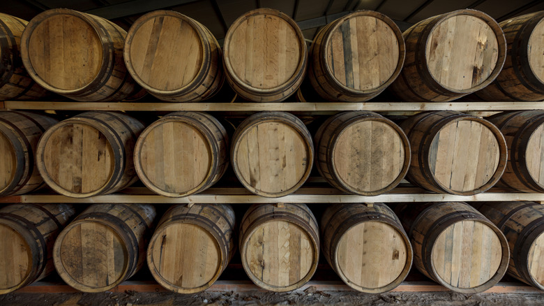 stacked rows of oak barrels in a whiskey warehouse