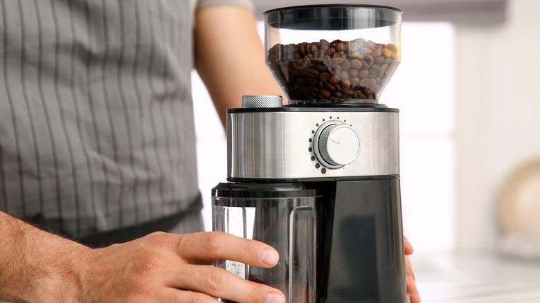 Hands holding a coffee bean grinder 