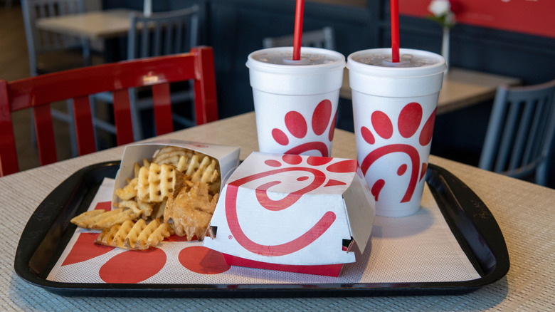 chick fil a sandwich with fries and two drinks on tray on table in restaurant