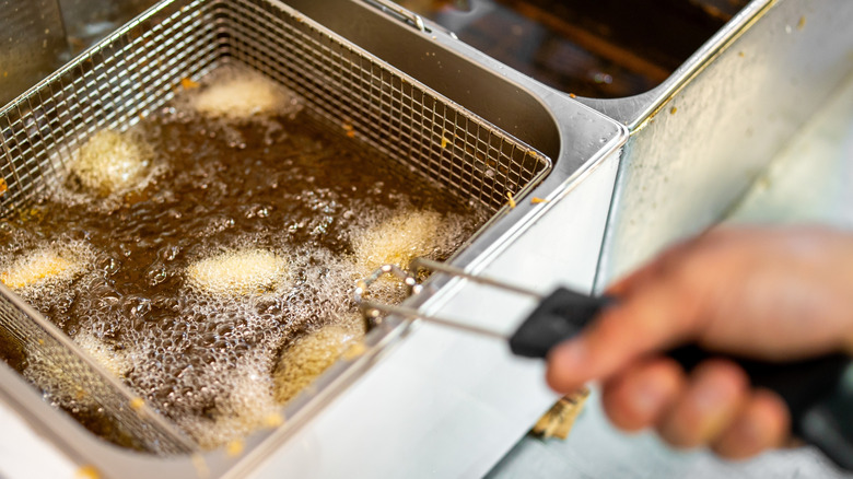 Fast food worker frying food in the commercial fryer.