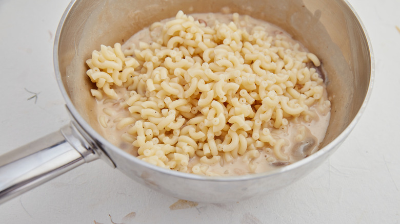 someone making box mac and cheese in pot