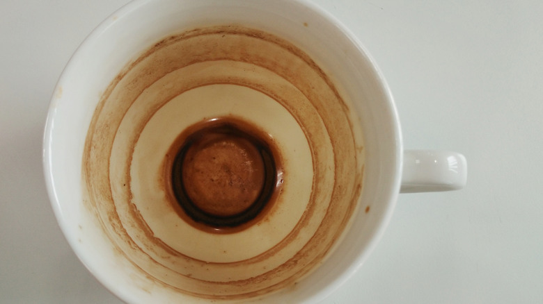 Overhead shot of white coffee cup with deep brown coffee stains.