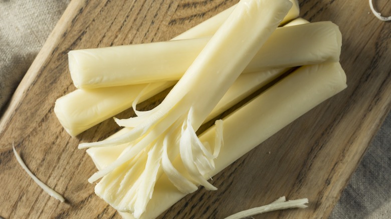 Close-up of several sticks of string cheese on a wooden block