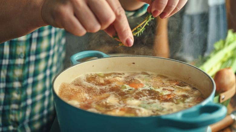 Woman preparing a soup broth in her kitchen