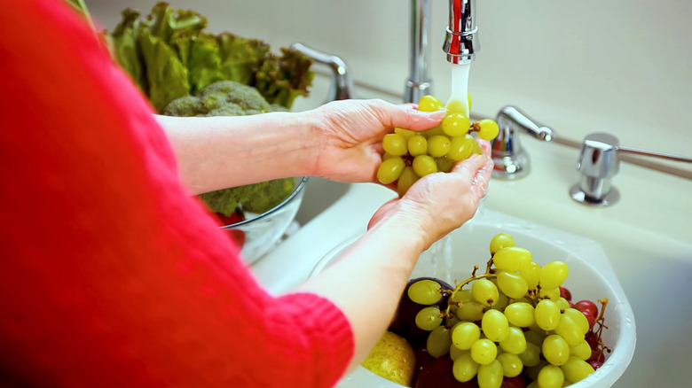 hands washing grapes in sink