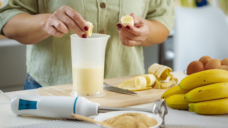 hands placing bananas in blender