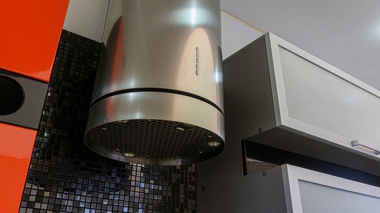 Low angle of a cylindrical aluminum oven hood and some cupboards