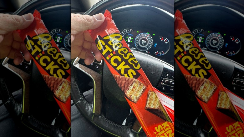 Hand holding Reese's Sticks in car