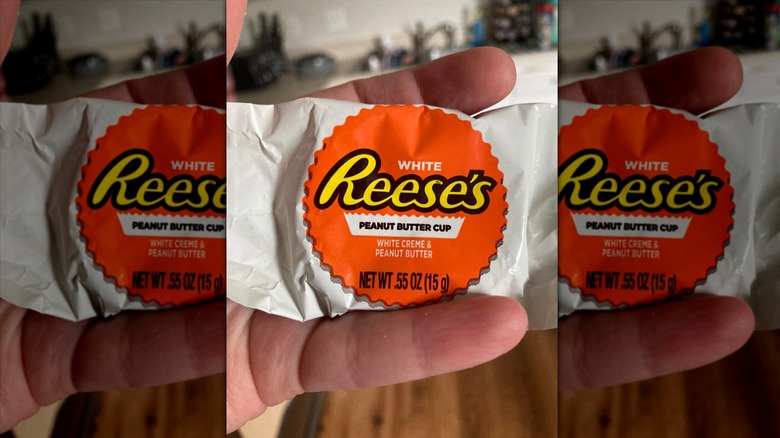 Hand holding Reese's White Creme Peanut Butter Cup in wrapper