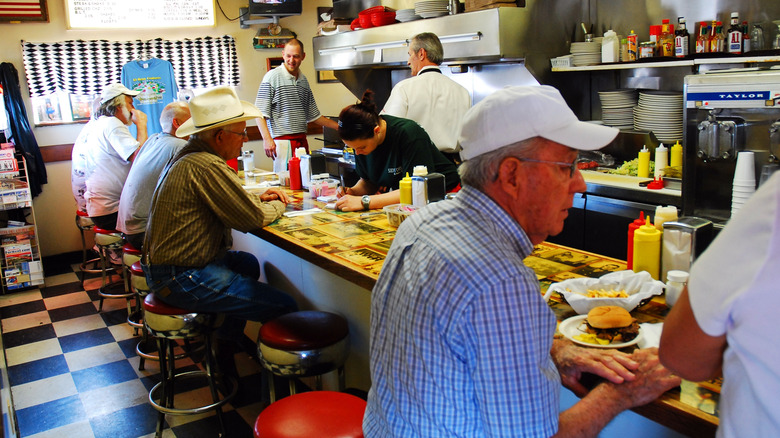 People sitting at a counter in a busy Diner.
