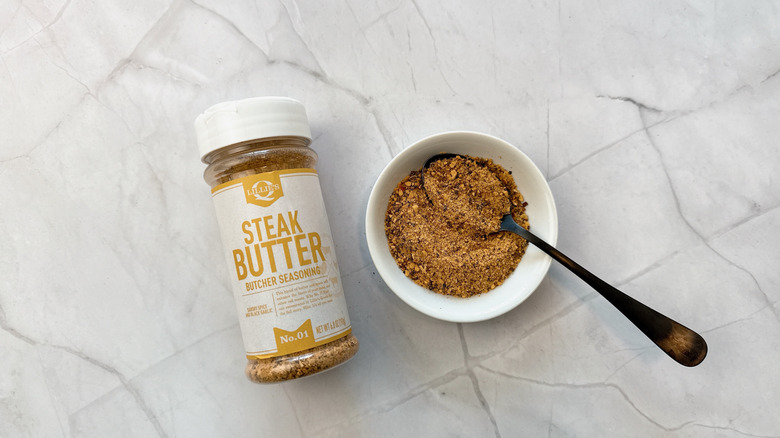 Bottle of Lillie Q's steak butcher butter seasoning next to some in a bowl with a spoon
