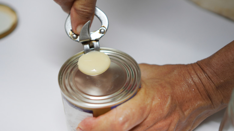 A person opens a can of sweetened condensed milk