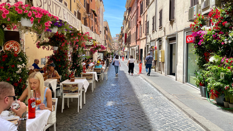 Couples dining on a colorful street with flowers in Rome, Italy