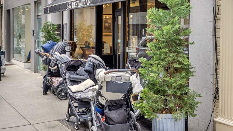 person holding baby in carrier at restaurant