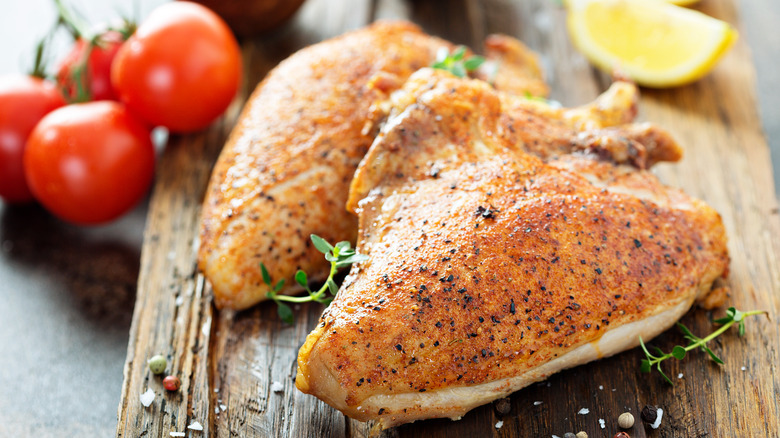 golden-skinned baked chicken breasts on the bone on a wooden board