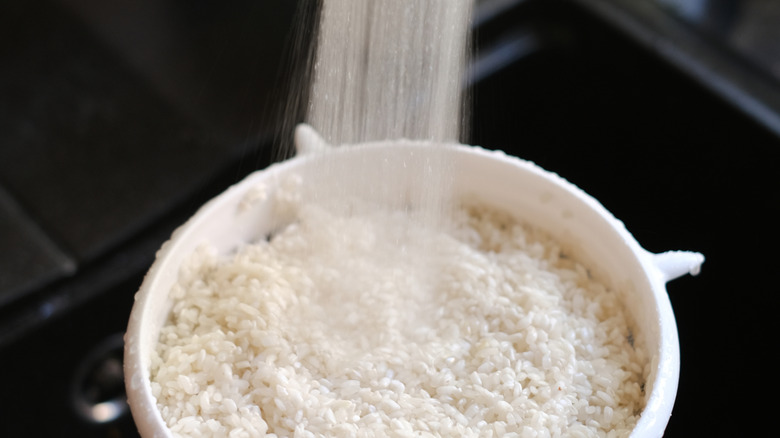 Person rinsing rice in a strainer with water