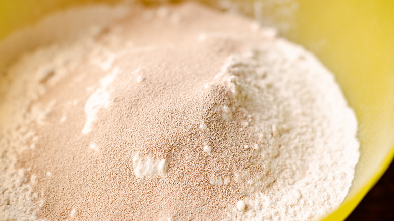 Closeup of instant yeast poured over flour in a mixing bowl