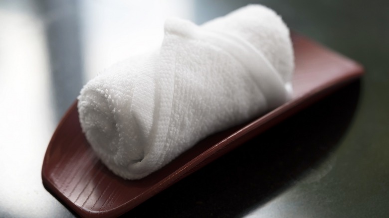 Small white towel rolled on tray