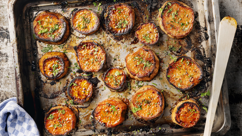 Overhead view of roasted sweet potato disks on a sheet pan