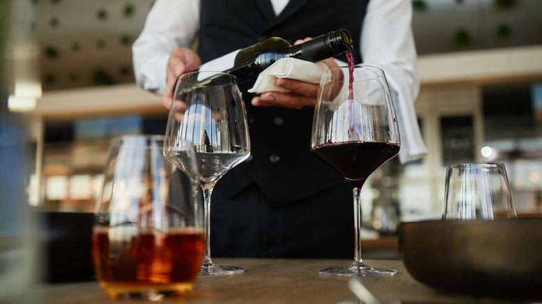 Waiter pouring wine into a long-stemmed glass at a restaurant