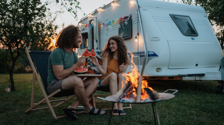 Couple eating watermelon around a campfire