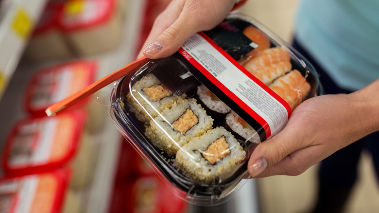 hands holding store-bought sushi