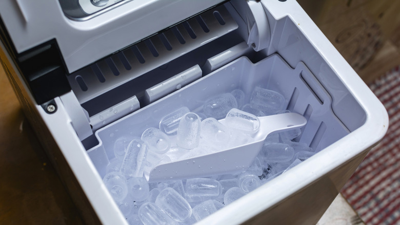 Portable ice maker with scoop inside