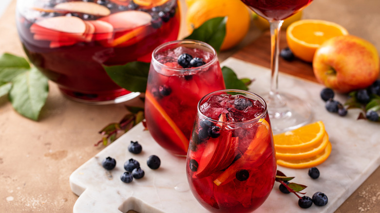 pitcher of red sangria with two glasses and garnishes