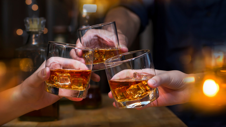Three whisky glasses clinking