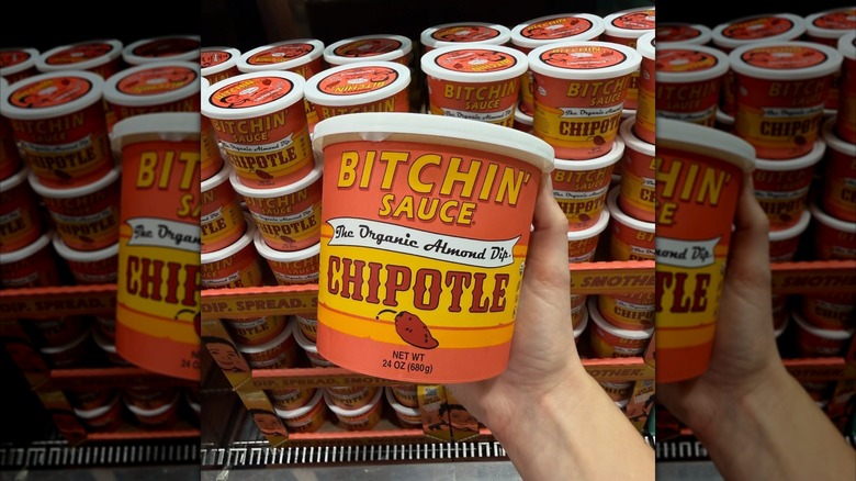 hand holding container of B***hin' Sauce at Costco