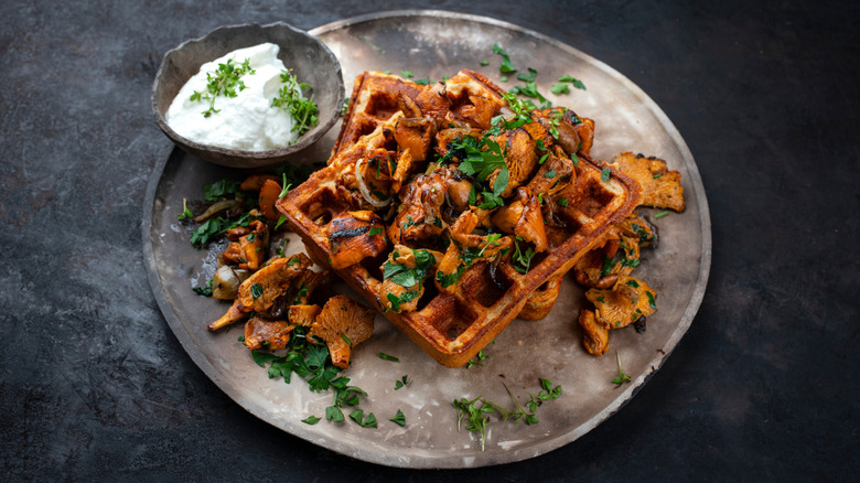 A plate of waffles with sautéed mushrooms on top