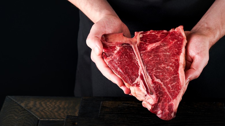 man holds raw steak cut