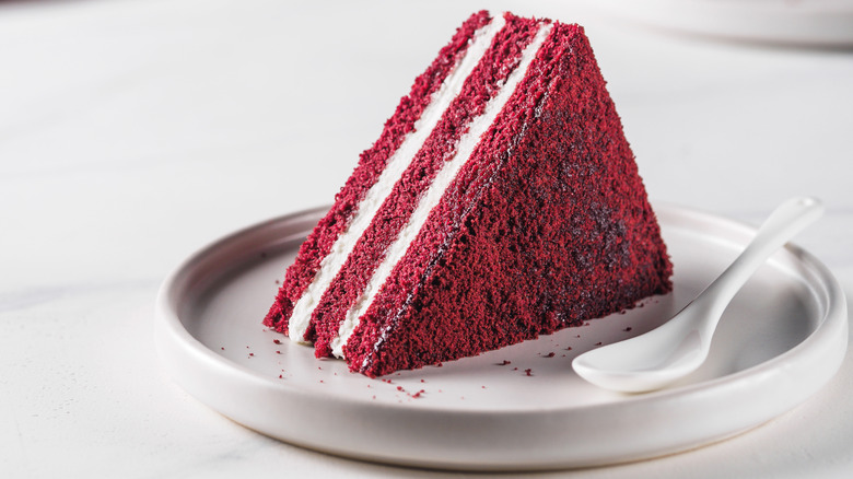 slice of red velvet cake with plate and spoon