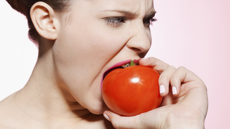 woman biting raw tomato